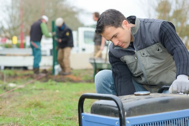 Man checks a portable generator to prepare his temporary power for a power outage.